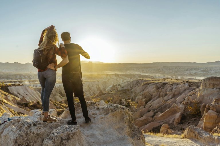 A couple enjoys a breathtaking sunrise view over the unique rock formations of Cappadocia, Turkey.