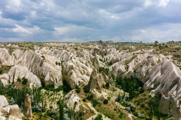 Aerial view of Cappadocia's unique rock formations under a cloudy sky, capturing nature's artistry.