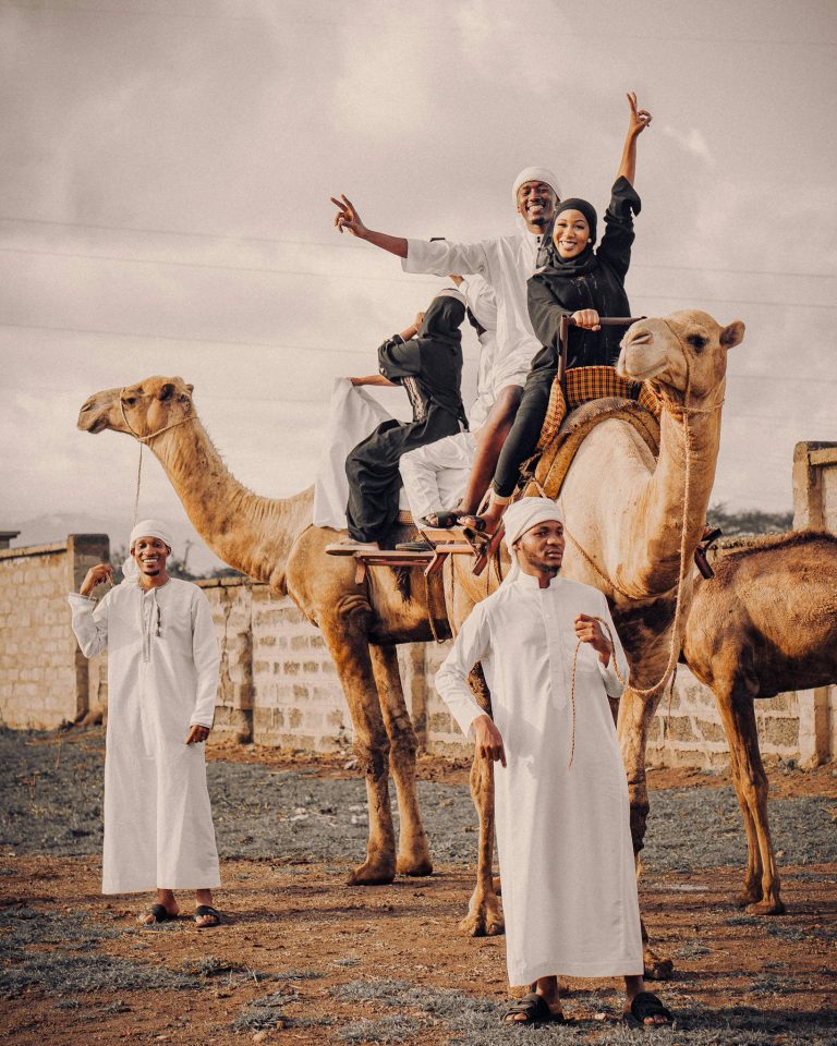 Group enjoying a joyful camel ride in a Middle Eastern setting with traditional attire.